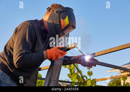 Male in face mask welds with argon-arc welding Stock Photo
