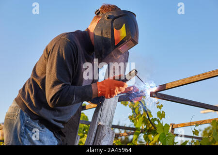 Male in face mask welds with argon-arc welding Stock Photo