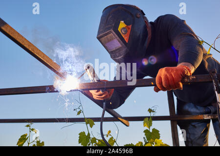Male in face mask welds with argon-arc welding Stock Photo