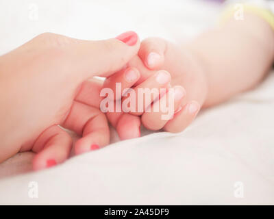 maternal hand holds her baby. Newborn children's hand in mother hand. Mom and her Child. Happy Family concept. Beautiful conceptual image of Maternity Stock Photo