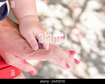 maternal hand holds her baby. Newborn children's hand in mother hand. Mom and her Child. Happy Family concept. Beautiful conceptual image of Maternity Stock Photo