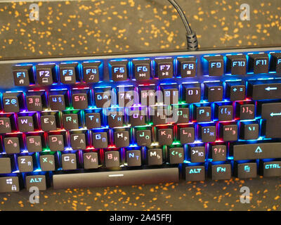 RGB keyboard. A colorful keyboard shimmers with different colors. lying on the table. Soft bokeh Stock Photo
