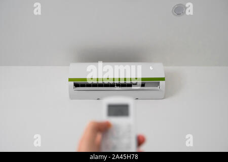 Man's hand using remote controler. Hand holding rc and adjusting temperature of air conditioner mounted on a white wall. Indooor comfort temperature Stock Photo