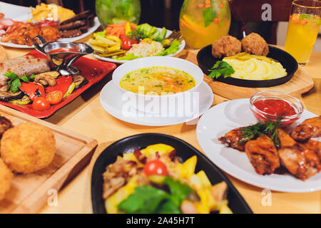 Dinner table with meat grill, roast new potatoes, vegetables, salads, sauces, snacks and lemonade, top view Stock Photo