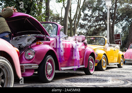 Hood of purple classic car open and man looking for something, yellow classic car in background Stock Photo