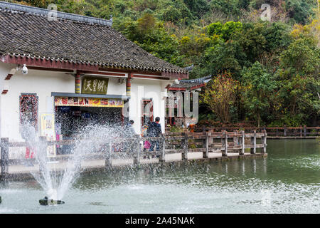 Gift shops in the Chinese ancient house with The Tianxing lake and fountain, in the National park of Huangguoshu waterfall, in Guizhou province of Chi Stock Photo