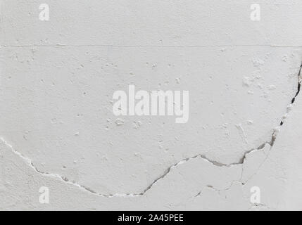 Close-up of a cracked concrete wall painted in white. High resolution full frame textured background. Stock Photo