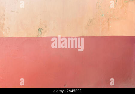 Full frame background of an old and weathered concrete wall painted in orange and red. Stock Photo