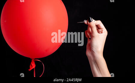 burst red balloon with a needle - danger concept Stock Photo