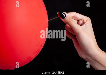 burst red balloon with a needle - danger concept Stock Photo - Alamy