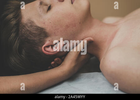 The man on the massage table is relaxing. The man before the massage feels calm and lies on a towel. Stock Photo