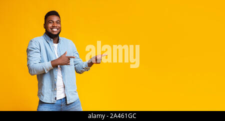 Cheerful black guy pointing two fingers aside at copy space Stock Photo
