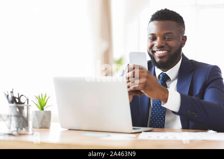 Cheerful businessman chatting with friends on phone, working in office Stock Photo