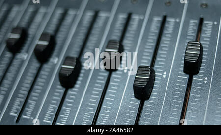 Multiple faders of a professional audio mixing console installed in a professional recording studio Stock Photo