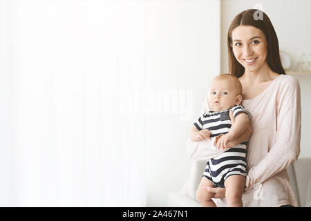 Portrait of happy mother with adorable baby on her hands Stock Photo