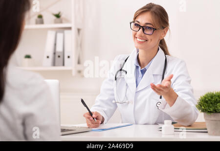 Smiling Therapist Talking With Unrecognizable Patient Sitting In Office Stock Photo