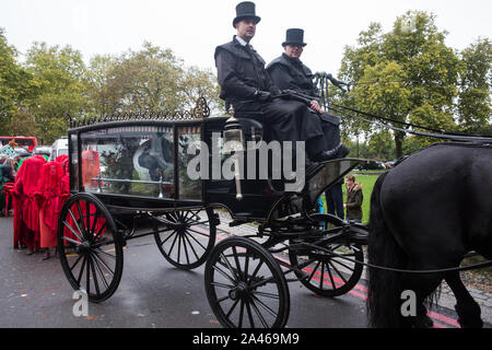 London, UK. 12 October, 2019. The Red Brigade assemble behind a horse-drawn hearse bearing a globe with thousands of fellow climate activists from Extinction Rebellion to take part in the XR funeral march from Marble Arch to Russell Square on the sixth day of International Rebellion protests to demand a government declaration of a climate and ecological emergency, a commitment to halting biodiversity loss and net zero carbon emissions by 2025 and for the government to create and be led by the decisions of a Citizens’ Assembly on climate and ecological justice. Credit: Mark Kerrison/Alamy Live Stock Photo