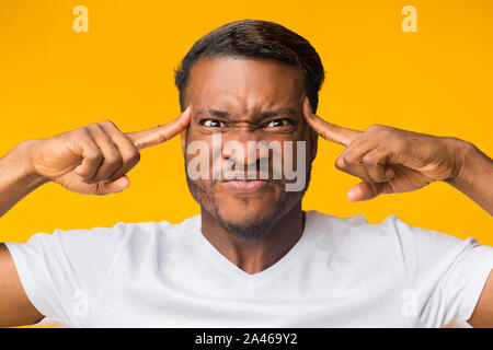 Black Man Concentrating Hard Pointing Fingers At Forehead In Studio Stock Photo
