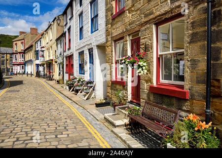 Colorful stone buildings in sunshine on cobblestone High Street in the seaside village of Staithes North Yorkshire England Stock Photo