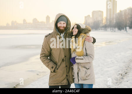 Theme love and date on nature. A young Caucasian heterosexual couple guy and girl walk in the winter along a frozen lake in winter. Bearded Man