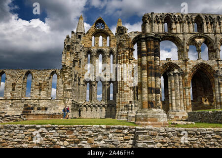 Tourists standing at the crossing of the North Transept in the Gothic ruins of Whitby Abbey cruciform church North Yorkshire England Stock Photo