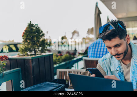 Businessman at airport with laptop and suitcase checking emails before boarding Stock Photo