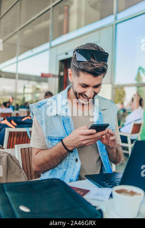 Businessman at airport with smartphone and suitcase checking emails before boarding Stock Photo