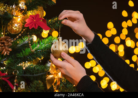 Girl decorates a Christmas tree. Closeup image of female hands decorating Christmas tree. Stock Photo