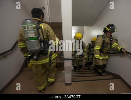 Firefighters with Commander, Navy Region Japan climb the stairs of a housing tower at Naval Air Facility Atsugi, Japan Stock Photo