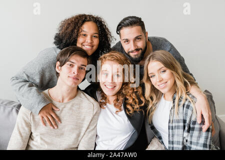 Young affectionate smiling friends in casualwear sitting in front of camera Stock Photo
