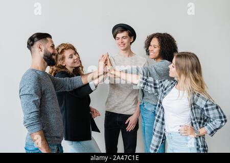 Group of young intercultural friends in casualwear making high-five Stock Photo