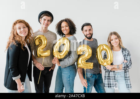 Group of multicultural friends holding golden balloons in form of numbers Stock Photo