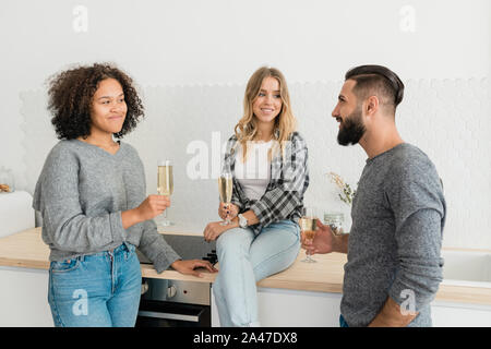 Three happy young friends with flutes of champagne making toast for holiday Stock Photo