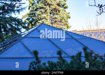 A pyramid-shaped skylight window appears on a rooftop terrace. The glass is seen in shadow, with a brighter background. Stock Photo