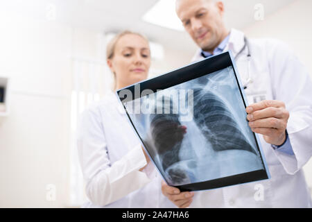 X-ray of lungs or spinal cors held by one of doctors during consultation Stock Photo