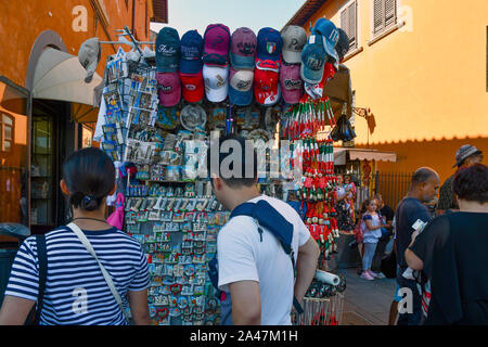 Tourists from behind buying souvenirs at a street stall in the old town of Pisa in summer, Tuscany, Italy Stock Photo