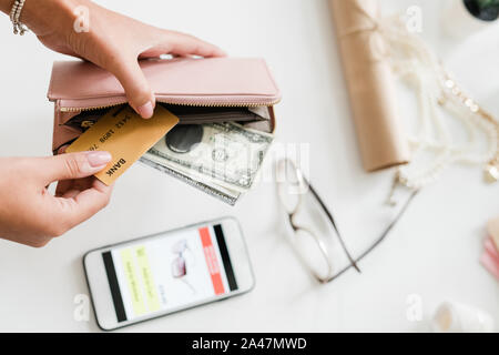 Hands of young woman holding leather wallet with dollar bills and plastic card Stock Photo