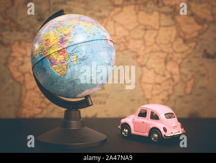 Vintage pink car and globe on a map background Stock Photo