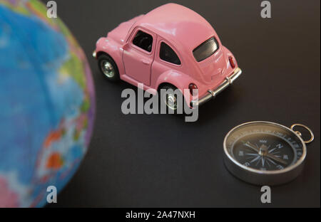 Car and globe with compass on black background, travel symbol around the world Stock Photo