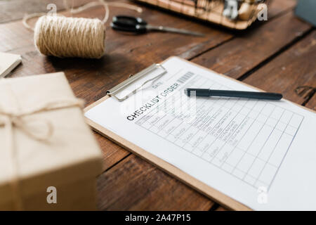 Clipboard with document and pen, spool of threads, packed box and other items Stock Photo