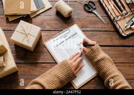 View of hands of young female putting ticks opposite ordered items in checklist Stock Photo