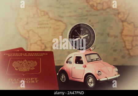 Small pink car with a compass on the roof and passports on a background of vintage maps, travel concept Stock Photo