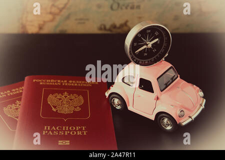 Small pink car with a compass on the roof and passports on a background of vintage maps, travel concept, view from above Stock Photo