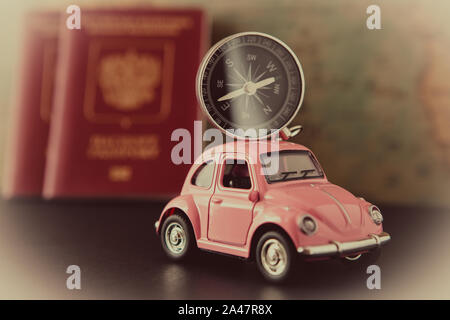 Close-up. Small pink car with a compass on the roof and passports on a background of vintage maps, travel concept Stock Photo