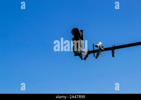 Traffic light with green color, outdoor surveillance camera and few sensors installed on a pole above a roadway. Modern automatic traffic control. Stock Photo