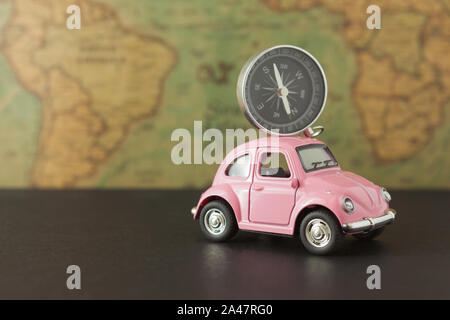 Pink car and compass on vintage map background, concept of travel and vacation planning Stock Photo