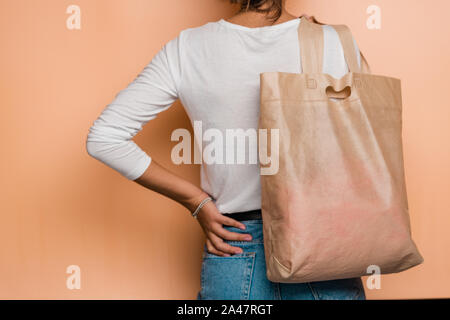 Rear view of young casual woman holding pinkish textile tote bag on shoulder Stock Photo