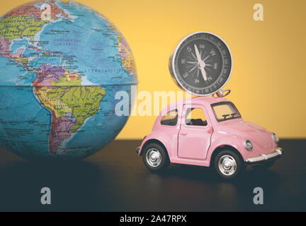 Pink retro car with world globe sphere on yellow background, toned photo Stock Photo