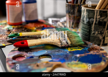 Group of paintbrushes and palettes on background of gouache jars Stock Photo