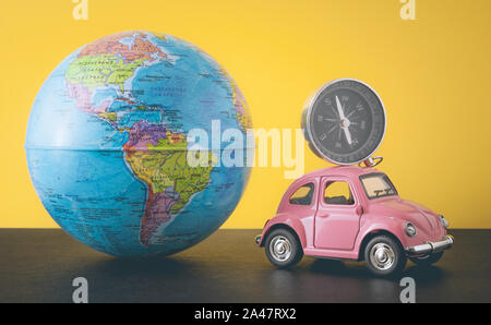Pink retro car and compass with world globe sphere on yellow background, toned photo Stock Photo